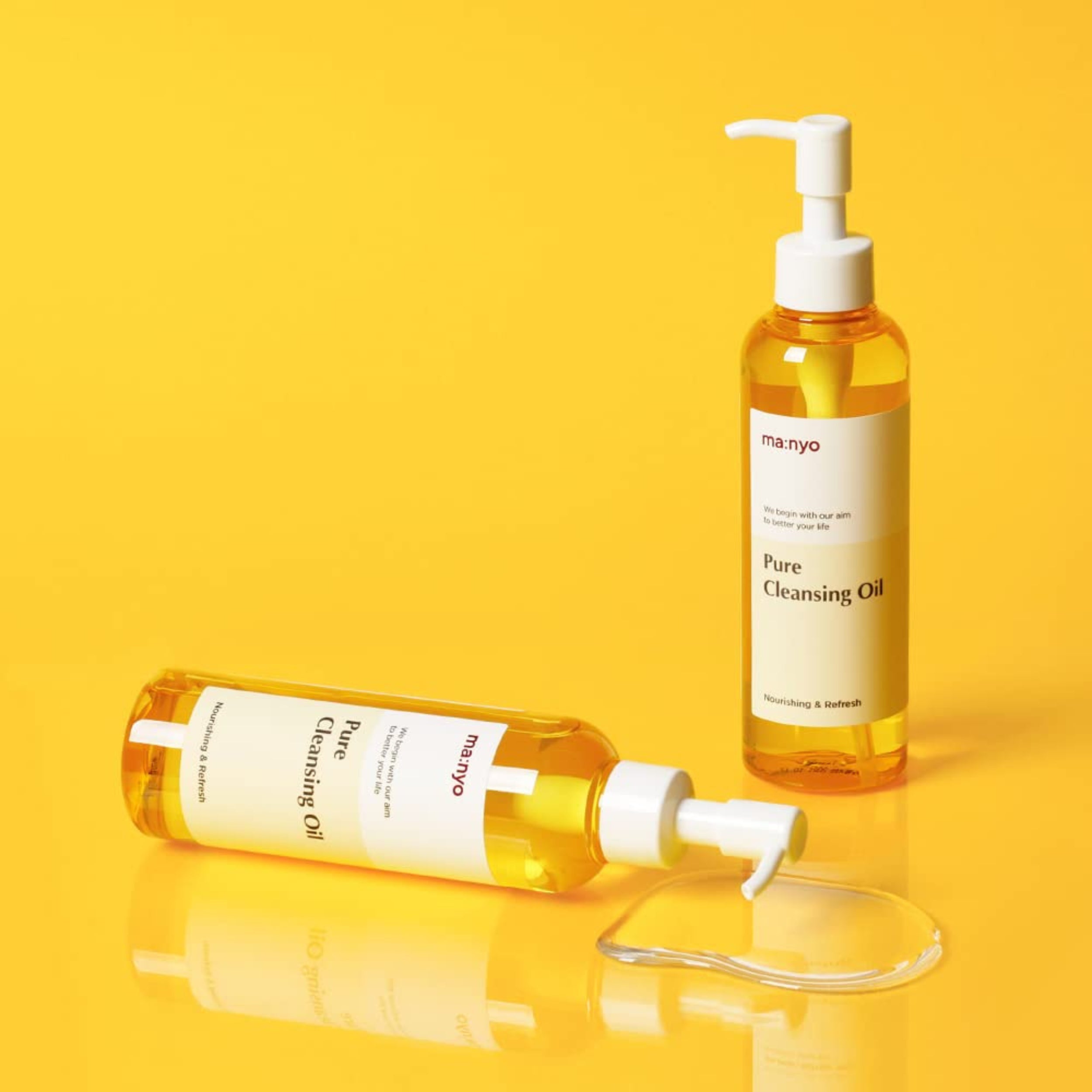 Two bottles of 'mamyo' Pure Cleansing Oil on a yellow background